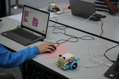 Henkilö käyttää kannettavaa tietokonetta ohjelmoidessaan robottia pöydällä.