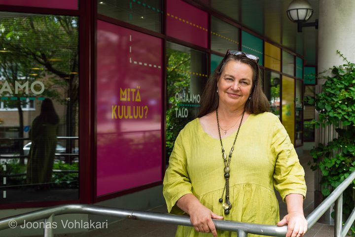 Kuvassa on Anne-Maria Laukkarinen. Hän seisoo ulkona Leppävaarassa sijaitsevan Ohjaamotalon sisäänkäynnin edessä.