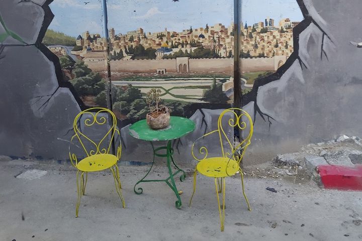 Kaksi keltaista tuolia ja vihreä pöytä Gazan muurin äärellä