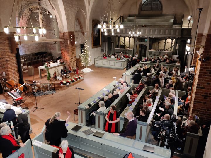 Esbo domkyrka inifrån och fotad från orgelläktaren så man ser människor i kyrkbänkar och den klädda julgranen.