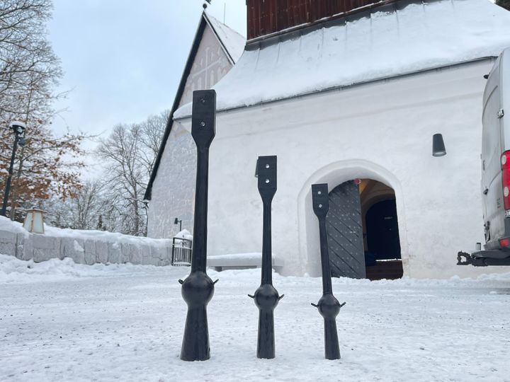 Kolme isoa kellon kieltä seisoo kellotapulin edessä lumisessa maisemassa.