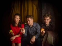 Kuvassa on kolme nuorta henkilöä. Jokainen heistä katsoo kädessään olevaa omenaa.