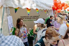 Suomen evankelis-luterilaisen kirkon esittelypiste Pride-tapahtumassa, jossa on värikkäitä lippuja ja iloisia ihmisiä.