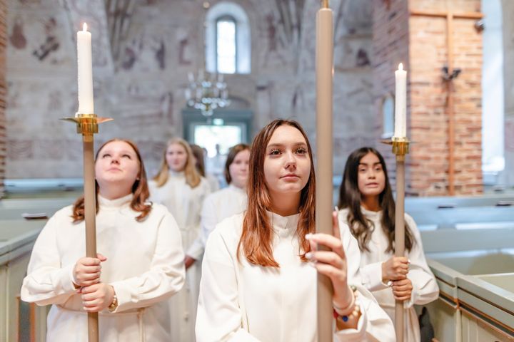 nuoria alboissa ristiä kantamassa Espoon tuomiokirkossa