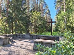 A memorial grove with a large cross and benches, along with a place for candles.