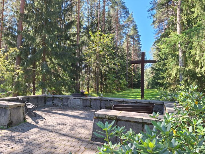 A memorial grove with a large cross and benches, along with a place for candles.