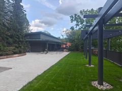 En mörk låg byggnad omgiven av natur och gräsmatta