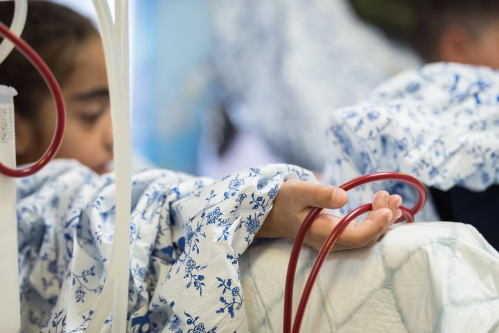 Ett barn eller ungdom med suddat ansikte och i närbild en arm med slangar för blodtransfusion.