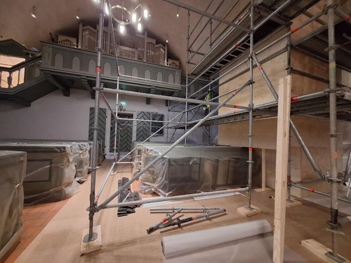 Orgelläktare och i kyrkorummet plastöverdragna kyrkbänkar och byggställningar.l
