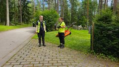 Två kvinnor står utomhus iklädda kläder för grönarbete.