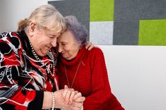 Två äldre gråhåriga kvinnor håller om varandra.