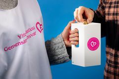 Hand holding a collection box and another hand putting money in it.