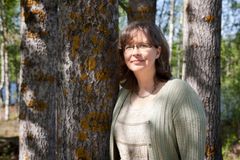 Kuvassa on Pauliina Kainulainen nojaamassa puuhun kesäisenä päivänä.