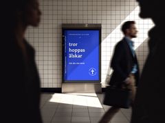 En affisch med texten "tror hoppas älskar" och "Gör din röst hörd", med rörliga människor i bakgrunden på en tunnelbanestation.