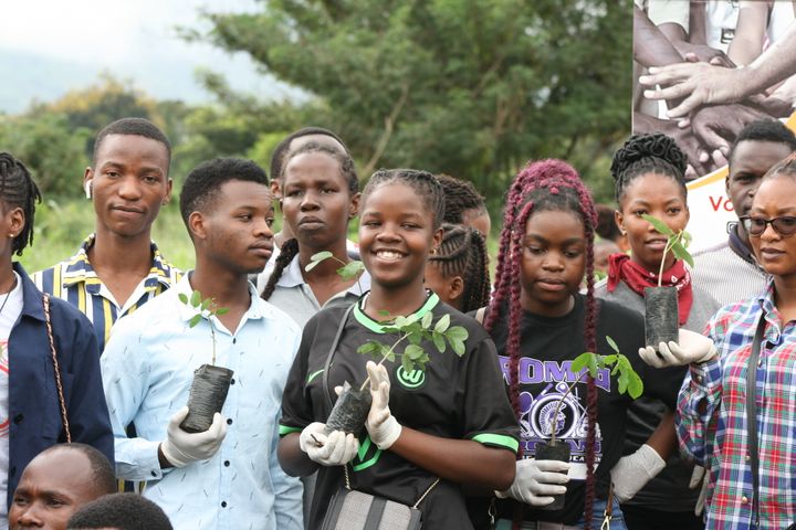 A group of young people with small tree plants in their hands.