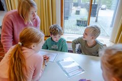 Neljäsluokkalaiset työskentelevät ryhmätyötehtävässä pöydän ääressä opettajan johdolla.