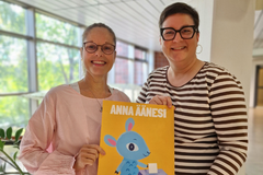 Två kvinnor håller i en affisch med uppmaningen: ge din röst och en illustration av ett lamm som lägger en valsedel i en valurna.