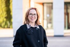 Nainen seisoo ulkona kampuksella.
