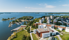 Ilmakuva Vaasan yliopiston kampuksesta, jota ympäröi vesi ja vihreä maisema.