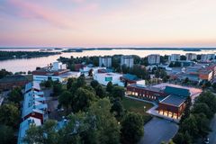 Ilmakuva Vaasan yliopiston kampuksesta meren rannalla, rakennuksia ja puita auringonlaskun aikaan.