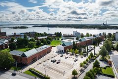 Ilmakuva rannikkokaupungista, jossa on punatiilisiä rakennuksia, pysäköintialue ja taustalla meri.