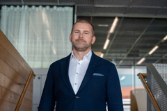Jukka Sihvonen seisoo portaissa yliopiston kampuksen sisätiloissa.