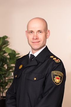 Henkilö pelastustoimen sinisessä virka-asussa katsoo kameraan.