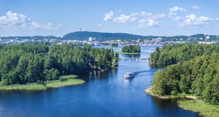 Maisema Kallavesi-järveltä Kuopiossa; järvi, pieniä saaria ja kaupunki horisontissa.