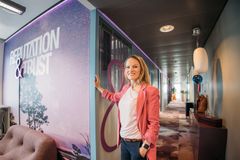 Salla Ketola seisoo Reputation and Trust Analyticsin toimistossa värikkään seinän edessä, jossa lukee "Reputation & Trust".