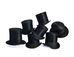 Seitsemän mustaa silinterihattua pinossa valkoista taustaa vasten.