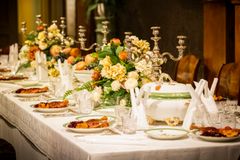 Joulukattauksella koristeltu pöytä, jossa on vanhanaikaisia astioita, kynttilänjalkoja ja kukka-asetelmia.