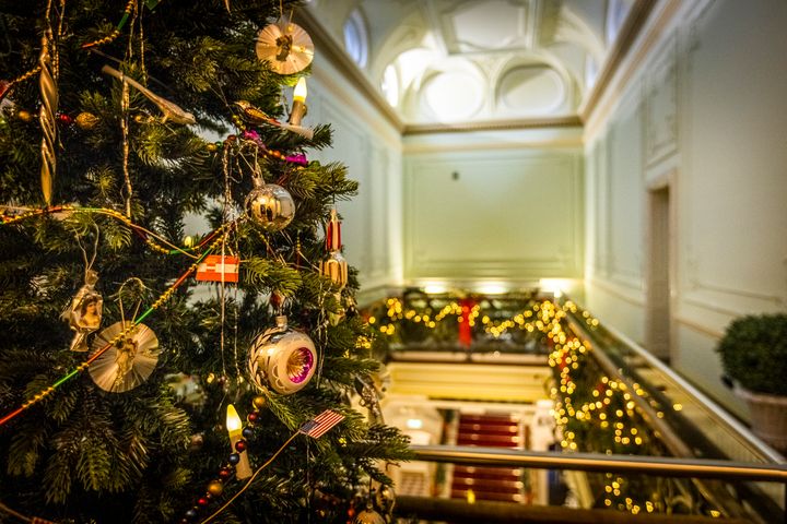 Jouluvaloin ja -koristein koristeltu palatsin käytävä, jossa näkyy joulukuusi etualalla.