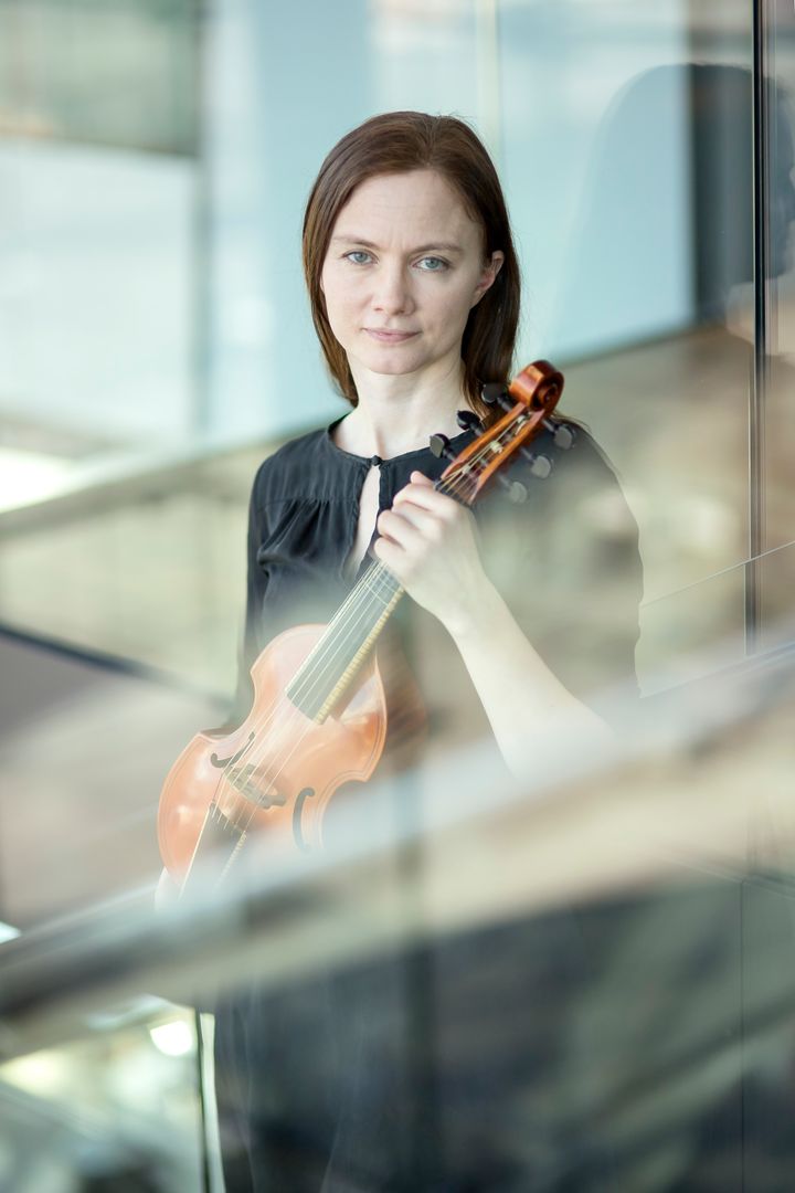 Kuvassa viulisti istuu ja katsoo kameraan.