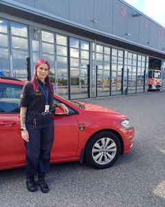 Palotarkastaja punaisen auton edessä.