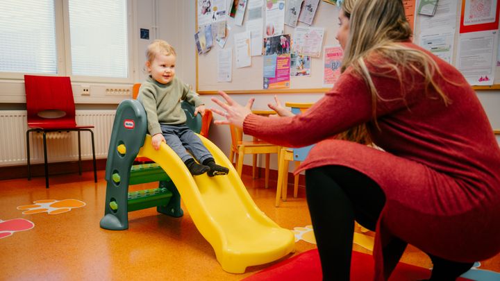 Henkilö ottaa vastaan pienen lapsen liukumäestä