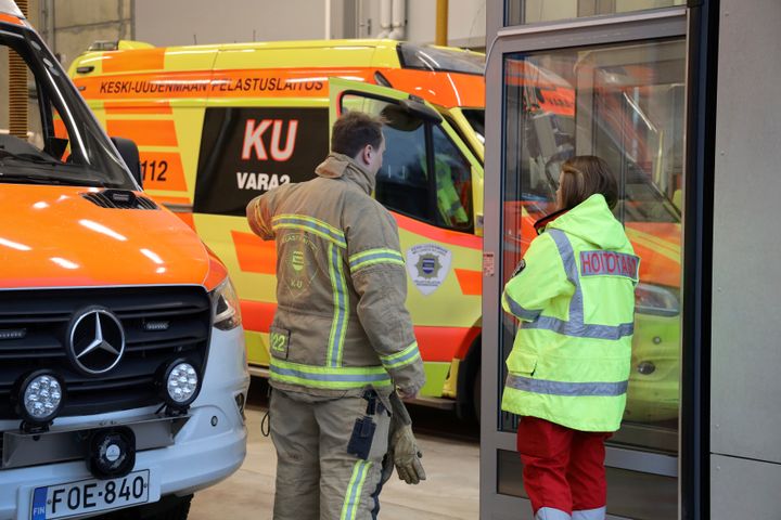 Palomies ja ensihoitaja neuvottelevat pelastysyksikön ja ensihoitoyksikön välissä.