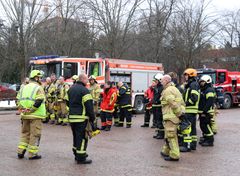 Sammutusasuihin pukeutuneita sopimuspalokuntalaisia kokoontuneena paloauton eteen.