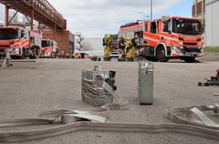 Paloautoja ja palomiehiä sekä paloletkuja.