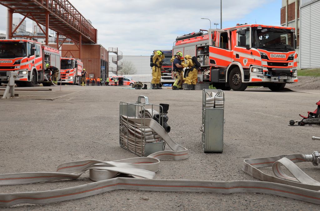 Paloautoja ja palomiehiä sekä paloletkuja.