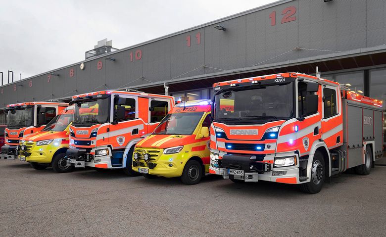 Kolme paloautoa ja kaksi ambulanssia vierekkäin paloaseman pihalla.