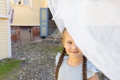 Tyttö hymyilee kameraan vanhan rakennuksen pihalla.