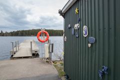 Kuva laiturista ja rakennuksen seinällä olevasta keramiikkateoksesta järven rannalla.