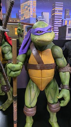 Ninja Turtle -hahmo, jolla on violetti silmämaski ja puinen keppi.