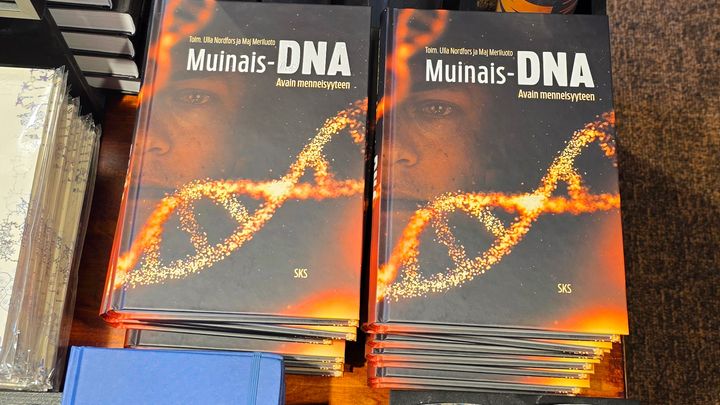 Kirjoja pinossa, kansissa lukee "Muinais-DNA - Avain menneisyyteen" ja näkyy DNA-ketju.