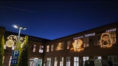 Vanha tiilirakennus, jonka julkisivua valaisee erilaiset valaistut kuviot, kuten orava ja maaorava, pimeää iltaa vasten.