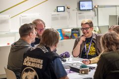 Ryhmällinen ihmisiä istuu pöydän ääressä ja pelaa roolipeliä.