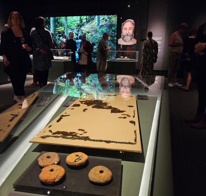 Näyttelytila, jossa on esillä muinaisia esineitä vitriineissä. Taustalla ihmisiä katselemassa näyttelyä.