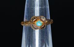 Alt text: Gold ring with black enamel and turquoise stone on display.