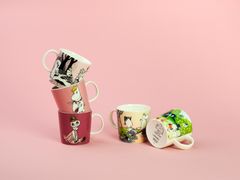 Valokuva pinotuista värikkäistä muumimukeista.