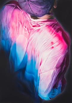 Henkilön yläselkä, johon osuu pinkki ja sininen valo.